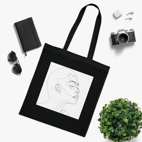 Minimalist black cotton tote bag with captivating line art face design.